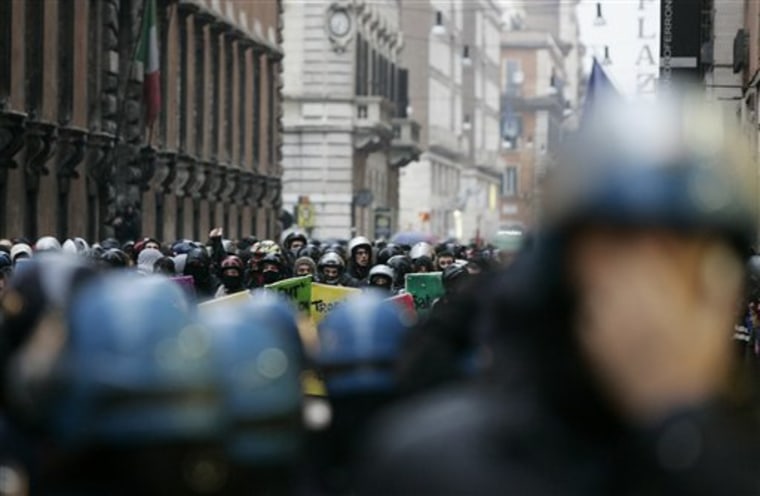 Demonstrators wearing helmets in background, face off against policemen in riot gear during a protest against the government-proposed education reforms which are being voted on in the Italian parliament, in Rome, on Tuesday.